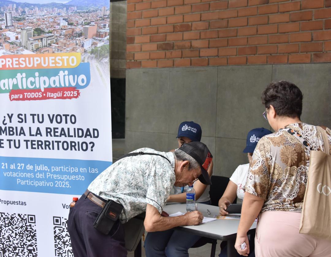 Dos personas votando en el presupuesto participativo en la Alcaldía, y dos funcionarios de la Alcaldía